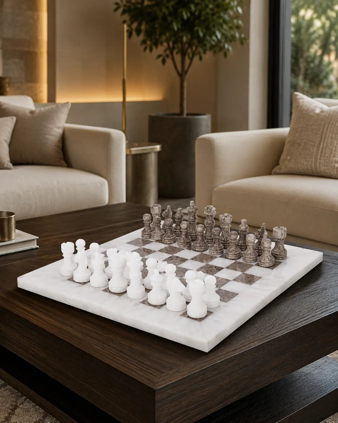 A marble chessboard with white and gray checkered squares and matching chess pieces, displayed on a dark wood coffee table in a modern living room setting.