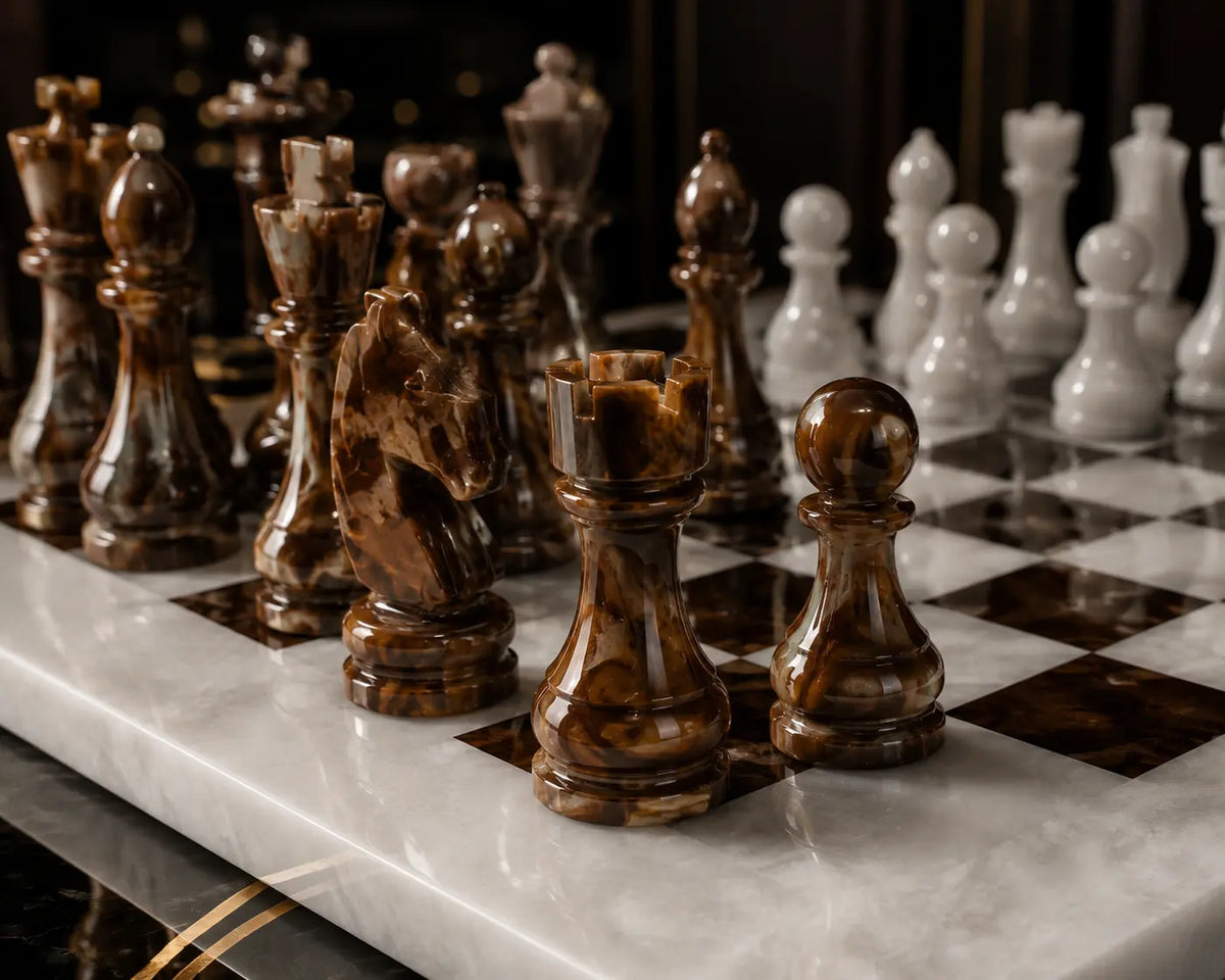 A close-up of a polished stone chess set on a marble chessboard, with glossy brown pieces in the foreground and white pieces in the background.